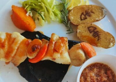 Table d'hôtes Bayeux dish: Grilled seafood skewer with potatoes, sweet potato, and vegetable garnish.