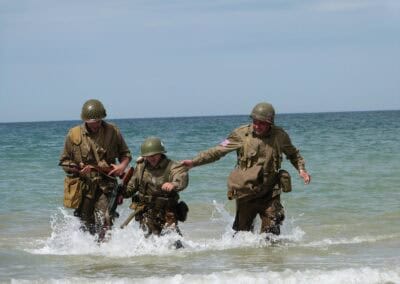 D-Day reenactors wade ashore in Normandy, France, recalling L'Histoire du Débarquement.