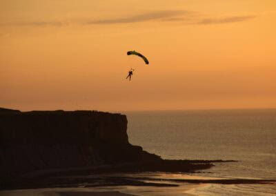 Paraglider over the Normandy coast at sunset, near the location of L'Histoire du Débarquement et de la Bataille de Normandie.
